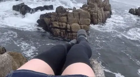 Pernas cruzadas em rochas na praia