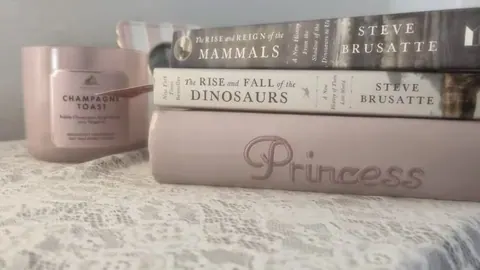 Pilha de livros e vela rosa